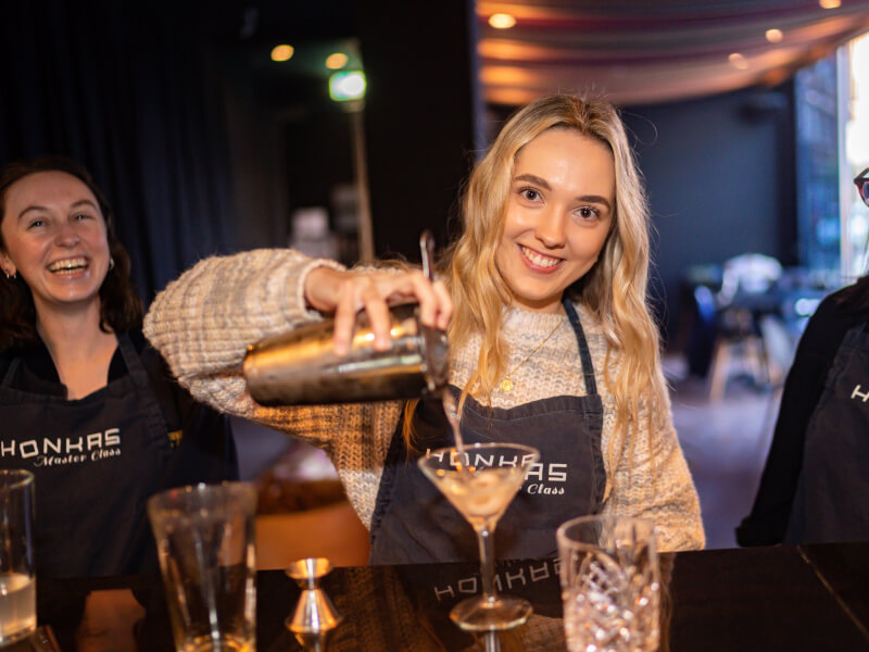 Woman smiling and pouring cocktail into glass